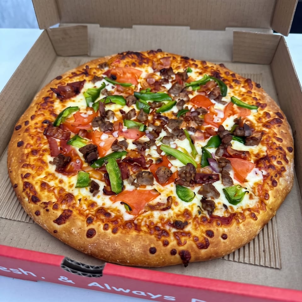 Pizza topped with meat, tomatoes and green peppers.