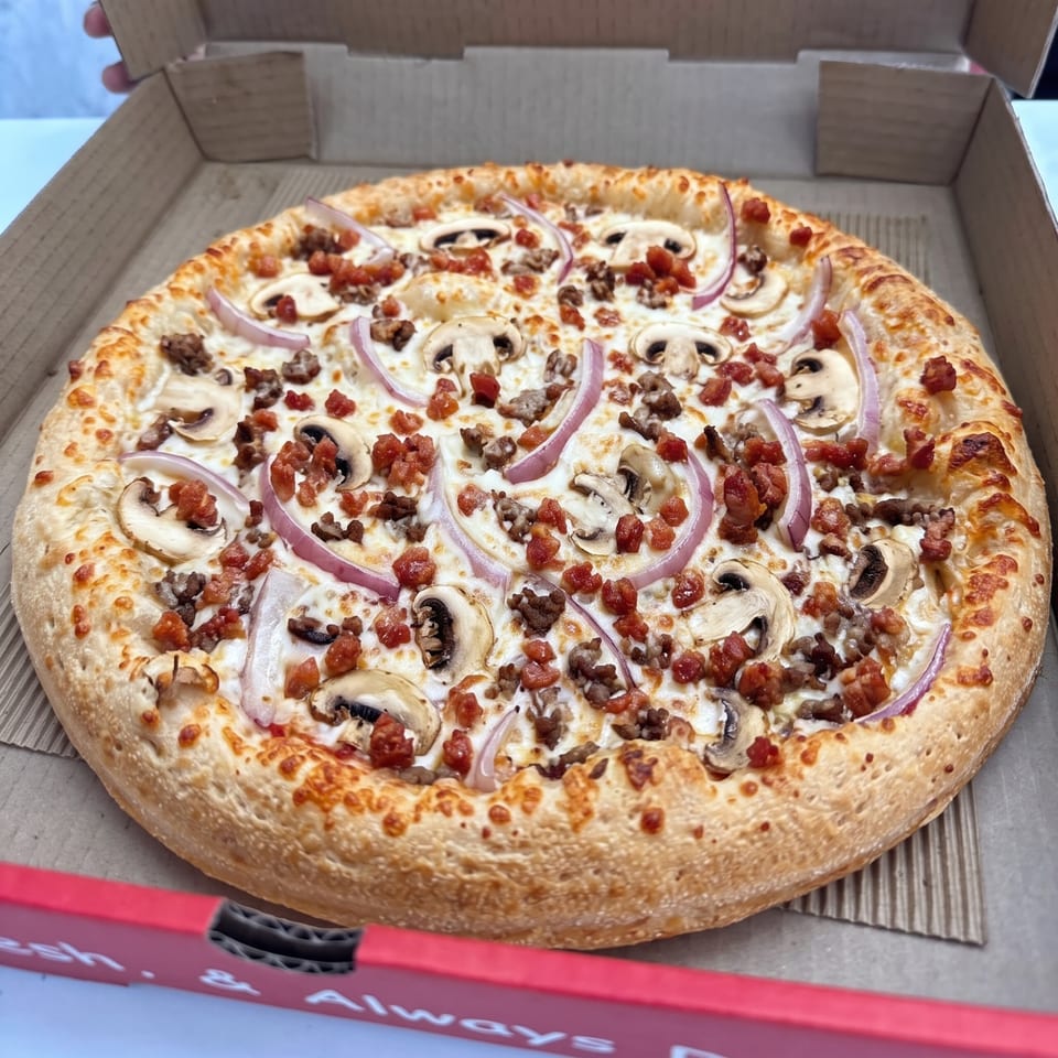 Pizza topped with mushrooms, red onions, and meat in a box without a phone number.