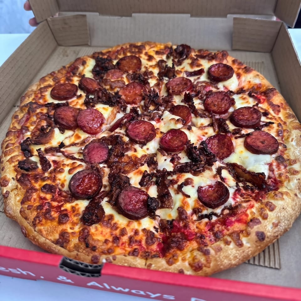 Pizza topped with sliced sausage and meat.