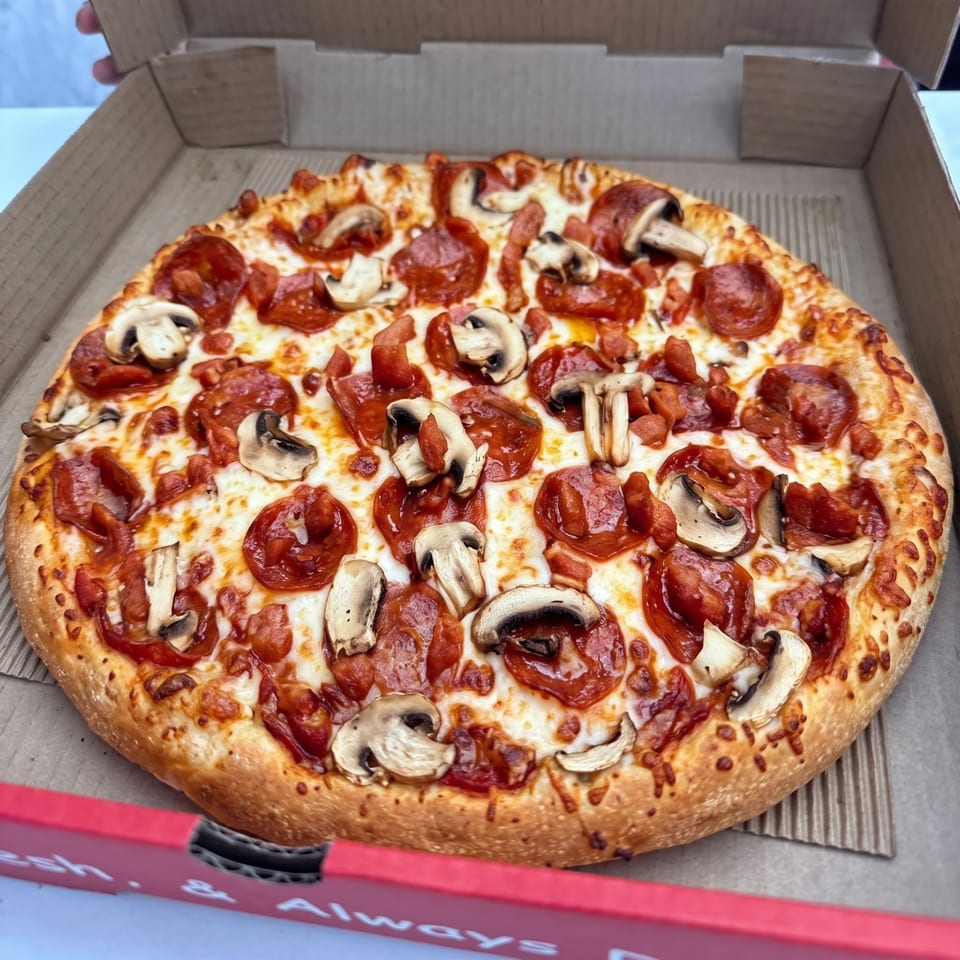 Pizza topped with mushrooms, pepperoni and diced meat.